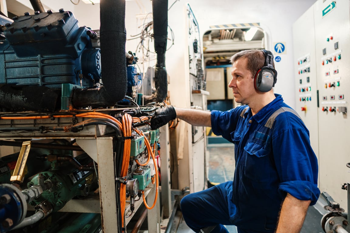 Marine engineer officer controlling vessel enginesand propulsion in engine control room ECR